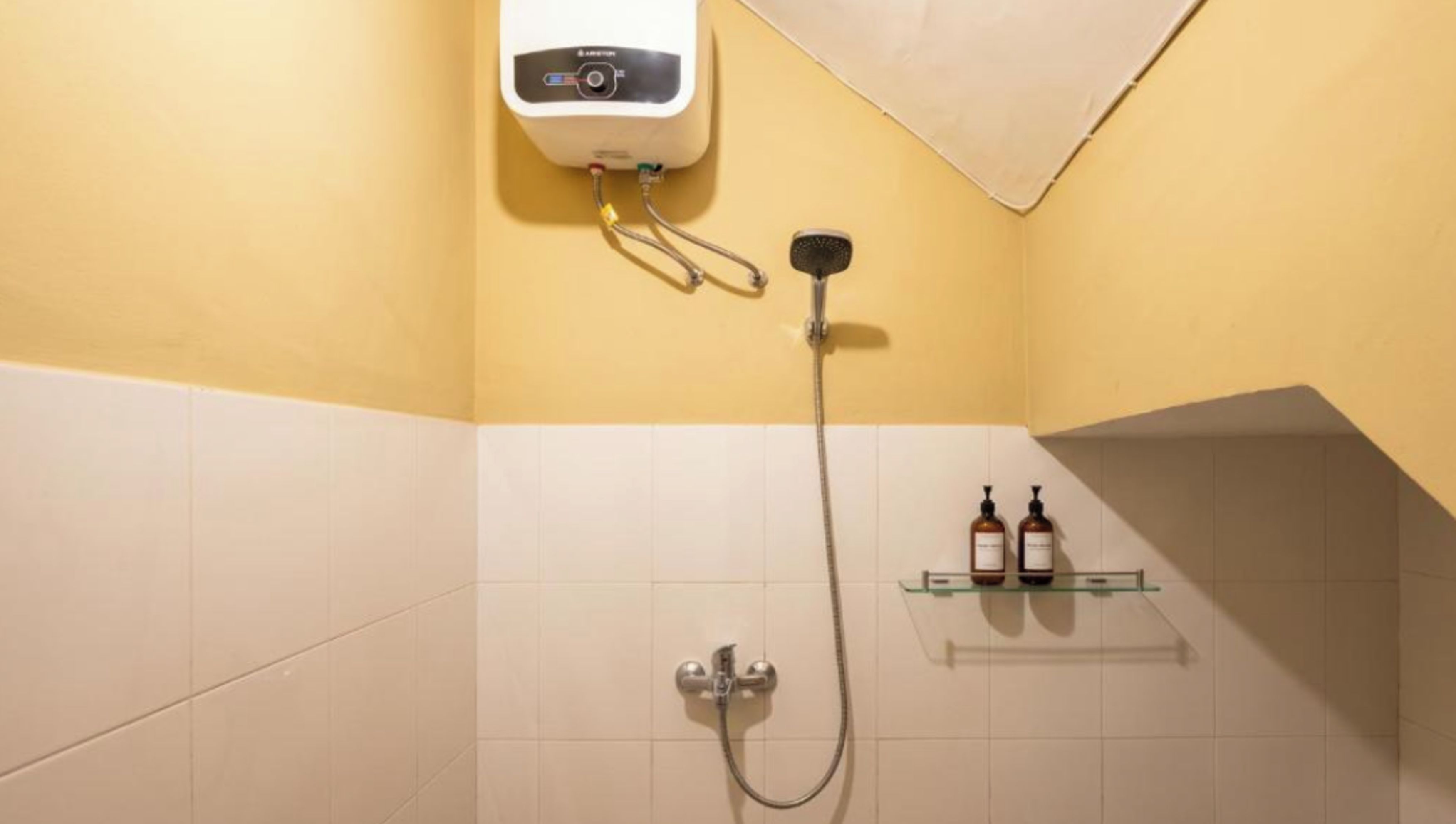 Un baño con ducha, un perchero y dos botellas en un estante.