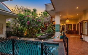 A pool area with a patio, lounge chairs, and a view of the garden. - GWK View Boutique Hotel and Residence (Jimbaran)