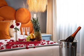 A bed with orange pillows, a vase with a rose, a pineapple, a bottle of champagne, and a fruit bowl. - Vibrant 3Bed Villa - A Deco Retreat (San Miguel de Allende)