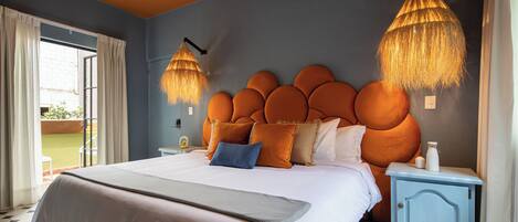 A bedroom with a large bed, a unique orange headboard, and two hanging lamps.