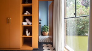 A room with a large wardrobe, a potted plant, and a view of greenery outside.