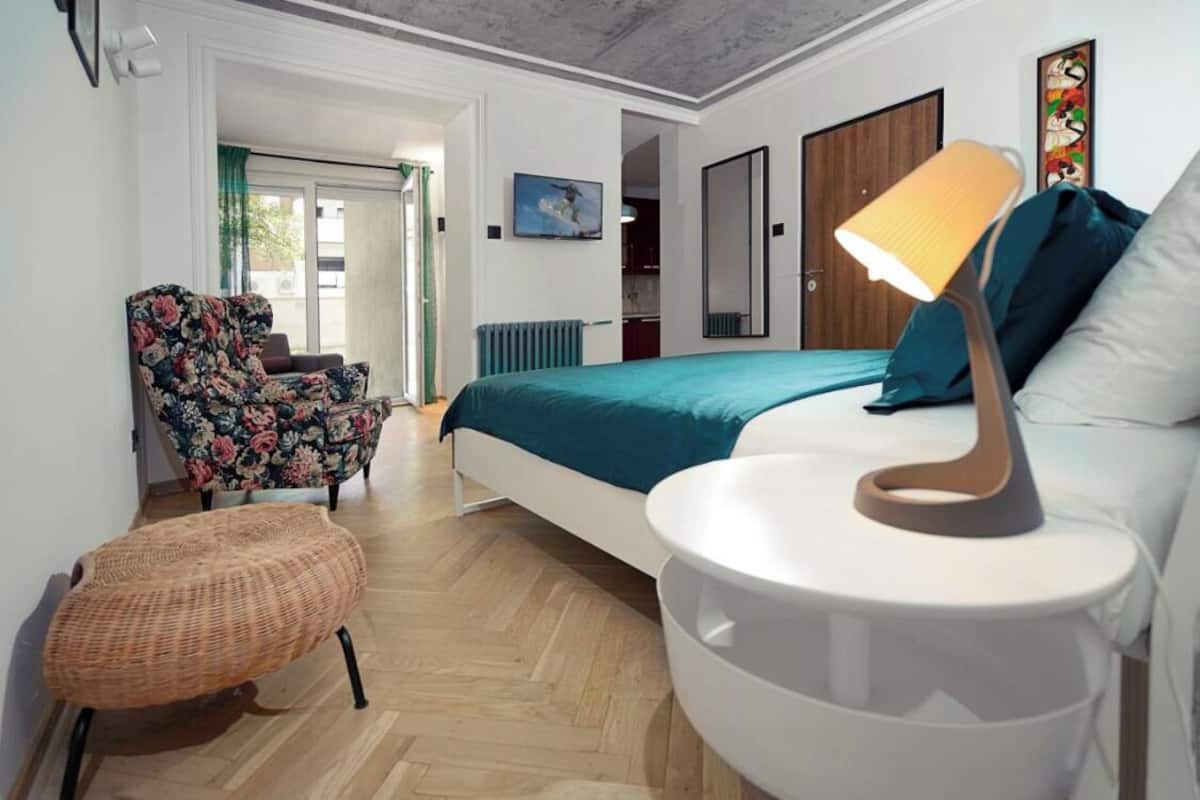 Une chambre à coucher avec un lit, une chaise, une lampe et une petite table.
