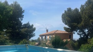 A clear swimming pool with a tiled edge, surrounded by trees and a building with a tiled roof. - Chambre Dhôte 2 Personnes à la Panouse, Marseille 13009 (Marseille)