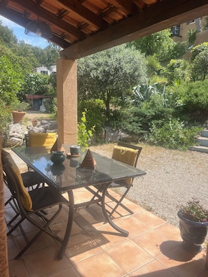 Eine Terrassenanlage im Freien mit einem Glastisch, Stühlen und Topfpflanzen.