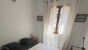 A bedroom with a bed, a nightstand, a lamp, a window with curtains, and a desk with a chair. - Chambre Dhôte 2 Personnes à la Panouse, Marseille 13009 (Marseille)