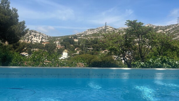 A swimming pool with clear water, surrounded by greenery and a mountainous backdrop. - Chambre Dhôte 2 Personnes à la Panouse, Marseille 13009 (Marseille)