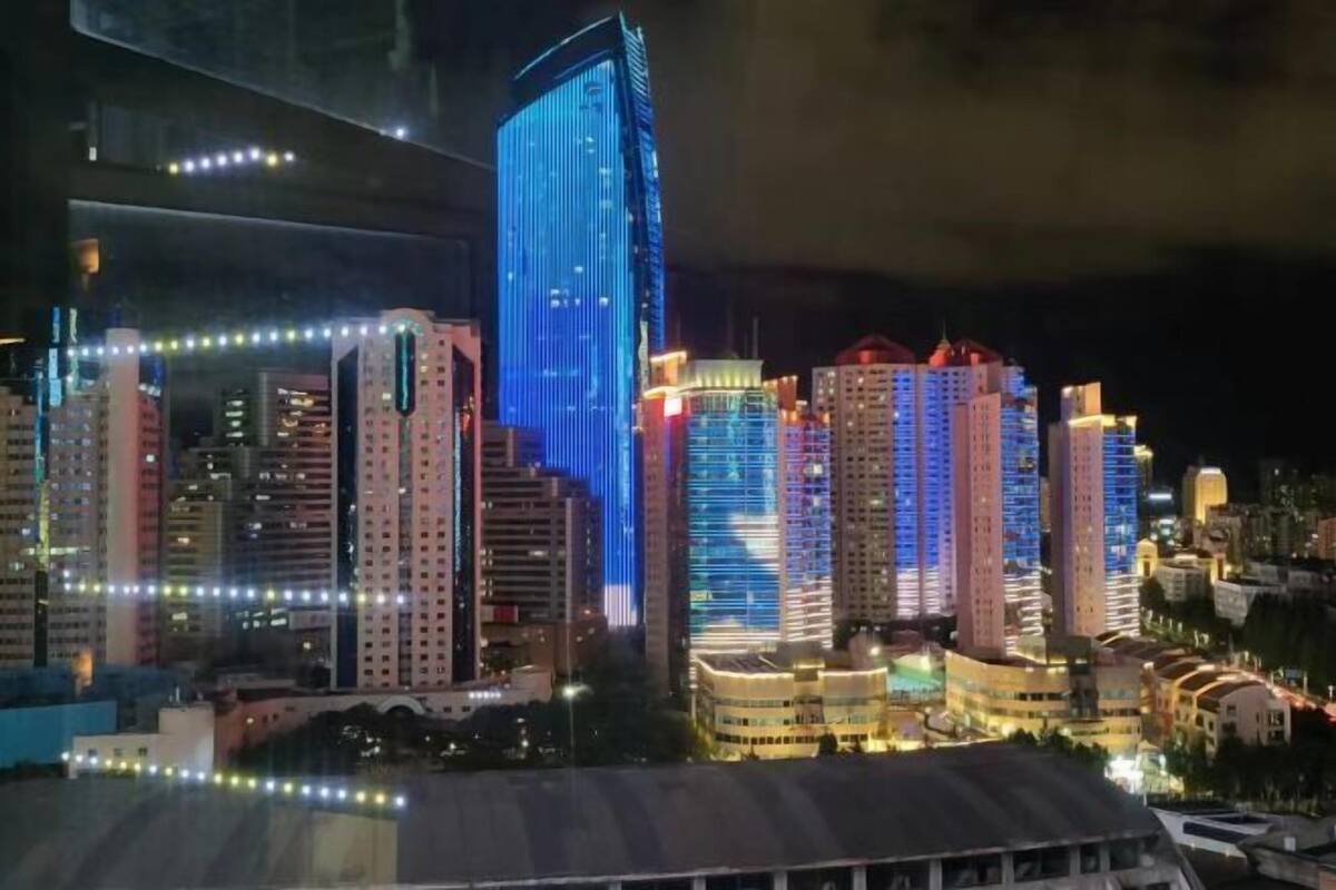 Een verlicht stadsbeeld 's nachts, met gloeiende wolkenkrabbers.