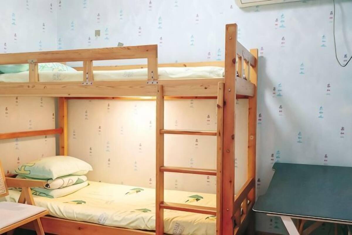Een slaapkamer met een stapelbed, een bureau en een tafel.