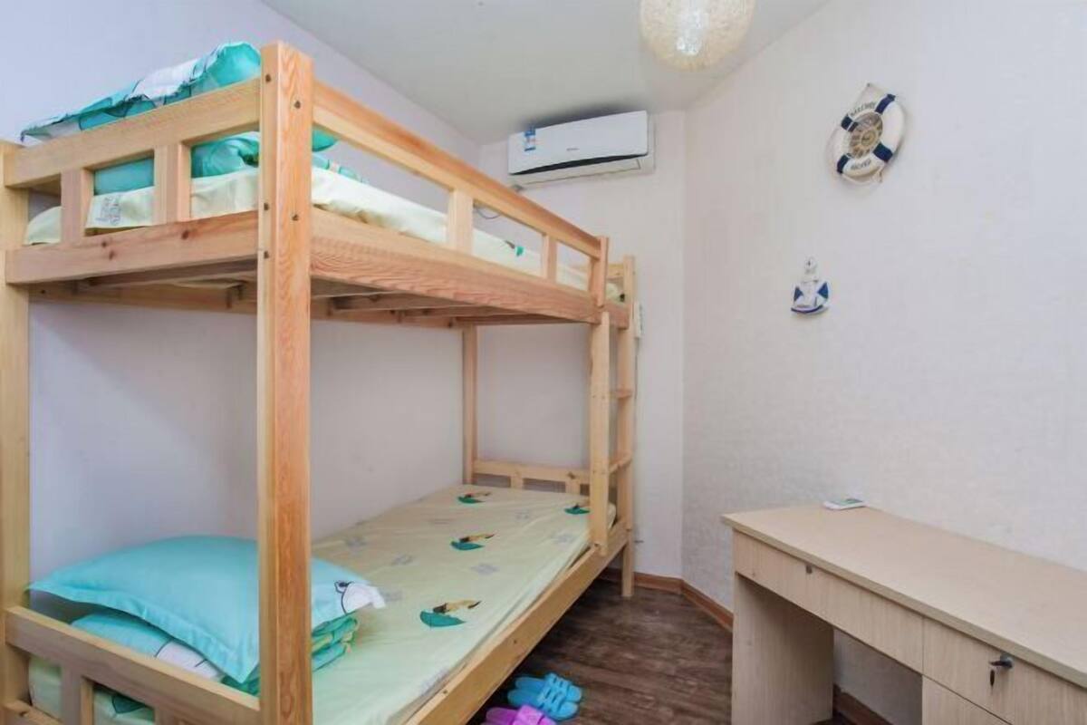 Een stapelbed met een bureau en een airconditioner in de kamer.