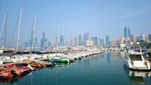 A marina with various boats docked, a city skyline in the background, and clear skies. - Qingdao Little Times Youth Hostel May4th Square Store (Qingdao)