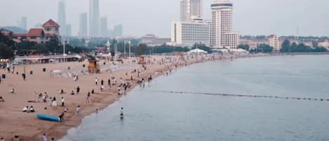 Une plage avec une longue étendue de sable et une mer calme, avec des bâtiments en arrière-plan.
