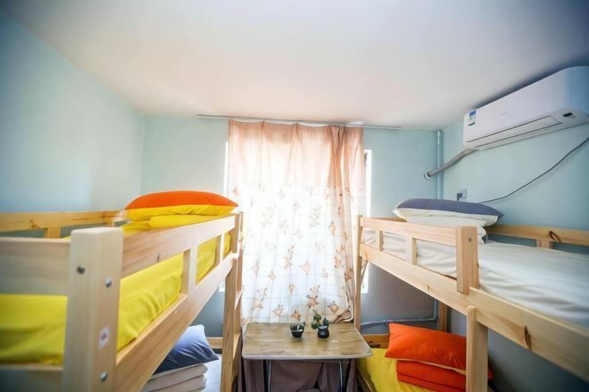 Een slaapzaal met stapelbedden, een tafeltje en een airconditioner.