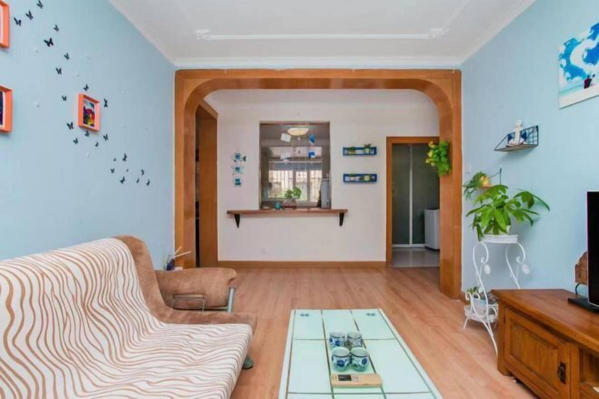 Een woonkamer met een bank, een salontafel en een tv-meubel. Er is een doorgang naar een andere kamer.