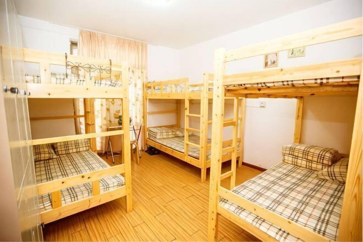 Een kamer met stapelbedden, houten vloeren en een gordijn.