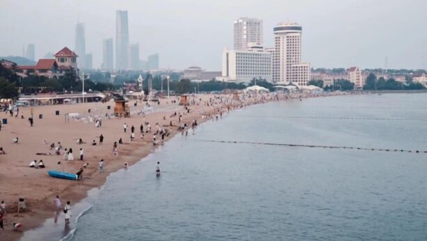 A beach with people and buildings in the background. - Qingdao Little Times Youth Hostel May4th Square Store (Qingdao)