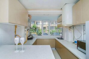 A kitchen with a window, white countertops, and a view of greenery outside.