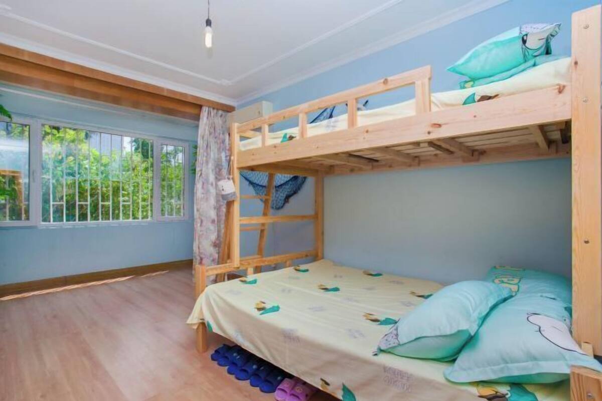 Een slaapkamer met een stapelbed, een raam, gordijnen en een houten vloer.