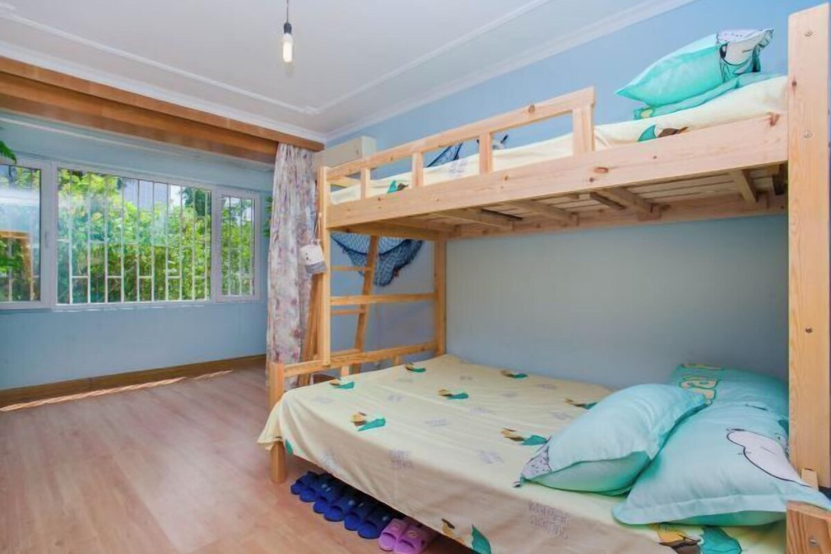 Camera con letto a castello, finestra, pavimento in legno e tenda.