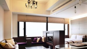 Una habitación de hotel moderna con sofá, televisión, mesa de comedor y cama.