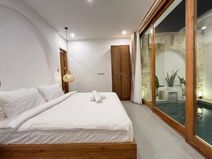 Ein modernes Schlafzimmer mit einem großen Bett, einem Holzkopfende und einer Glastür zum Poolbereich.