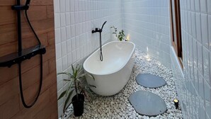 Ein modernes Badezimmer mit einer freistehenden Badewanne, einer Duschbrause und einem Oberlicht.
