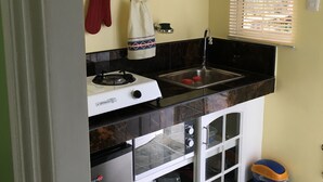 Une cuisine de taille réduite équipée d’une cuisinière à gaz, d’un évier et de placards de rangement.
