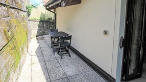 A patio area with a table and chairs, a door, and a stone wall. - Il Covo Felice by Interhome (Gravellona Toce)