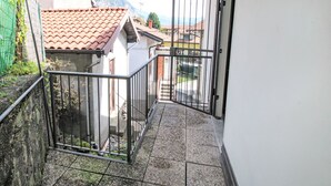 A narrow outdoor corridor with a tiled floor, metal railings, and a gate leading to a courtyard. - Il Covo Felice by Interhome (Gravellona Toce)