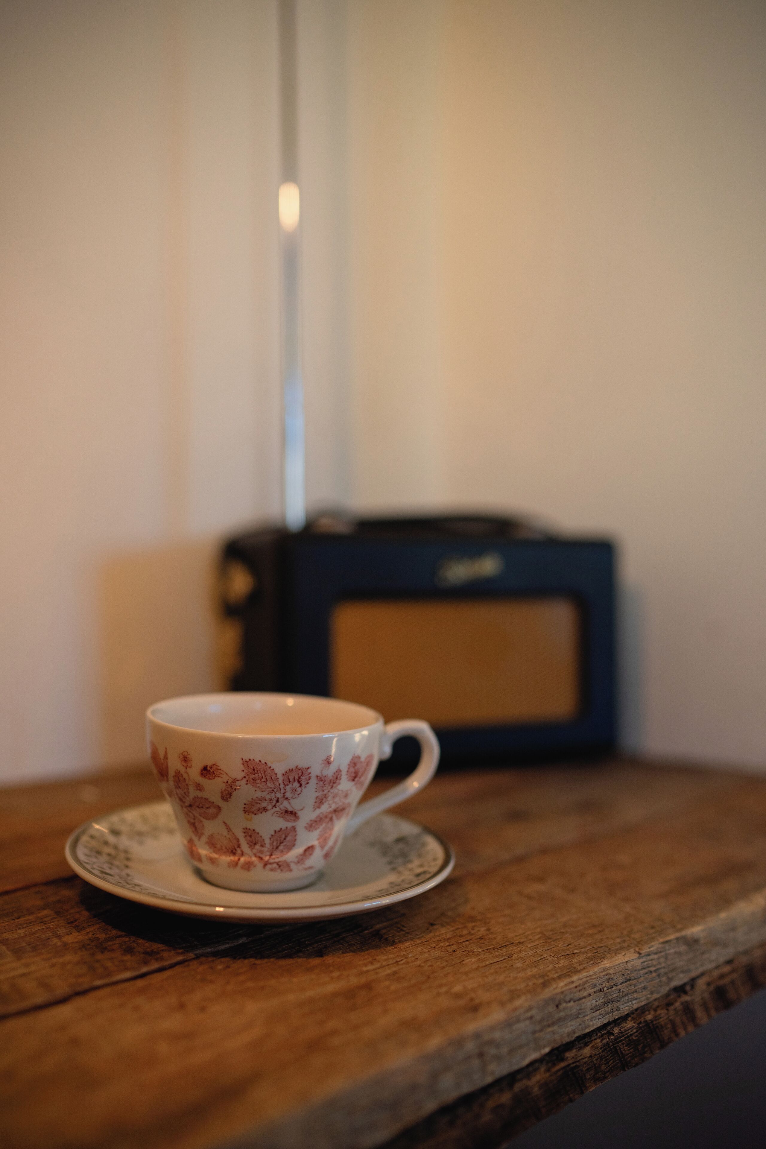 Una taza con motivos florales sobre un plato posado en una mesa de madera.