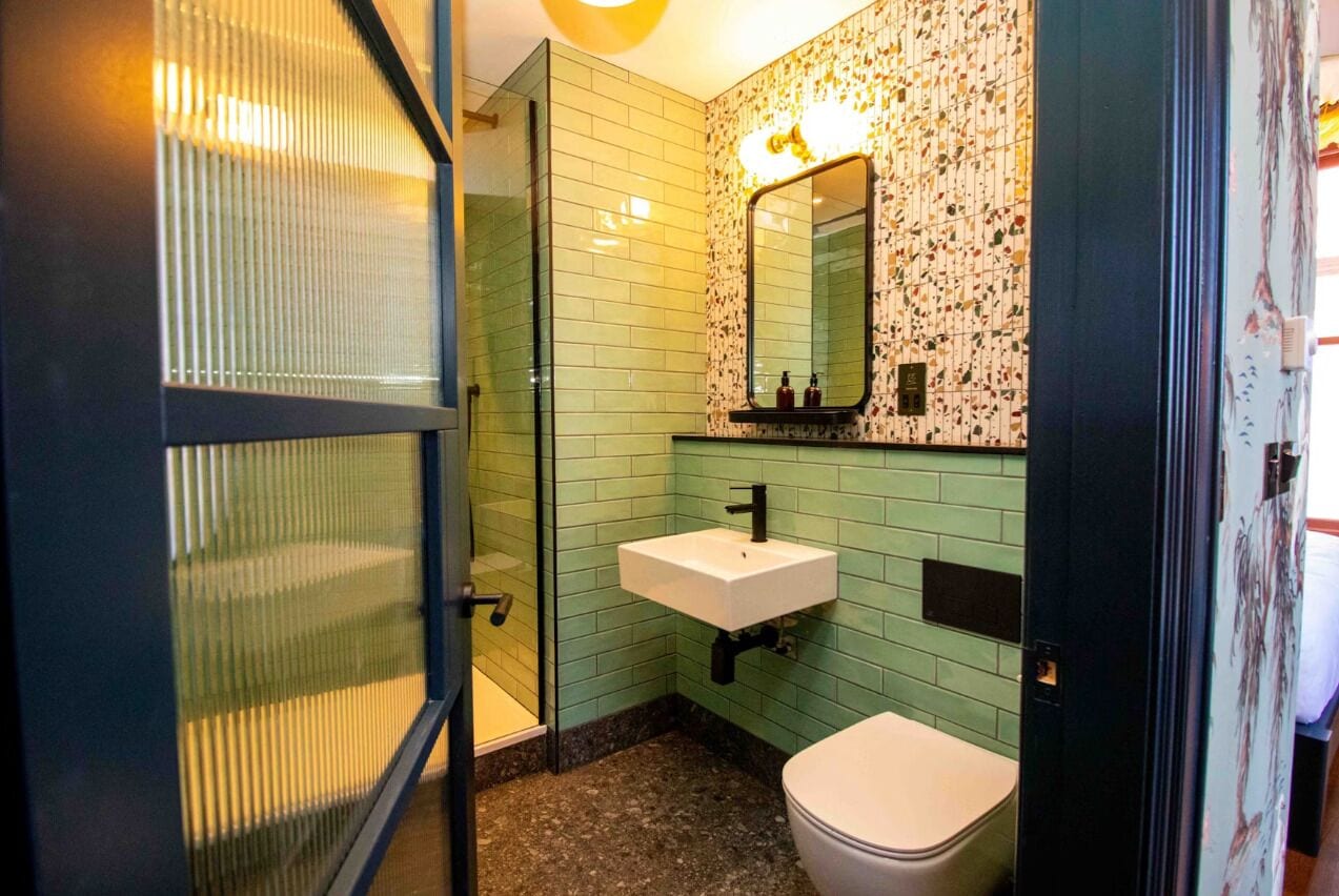 A bathroom with a glass shower enclosure, a white sink, and a toilet.