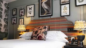 A neatly made bed with a floral pillow, two bedside lamps, and framed artwork on the wall.
