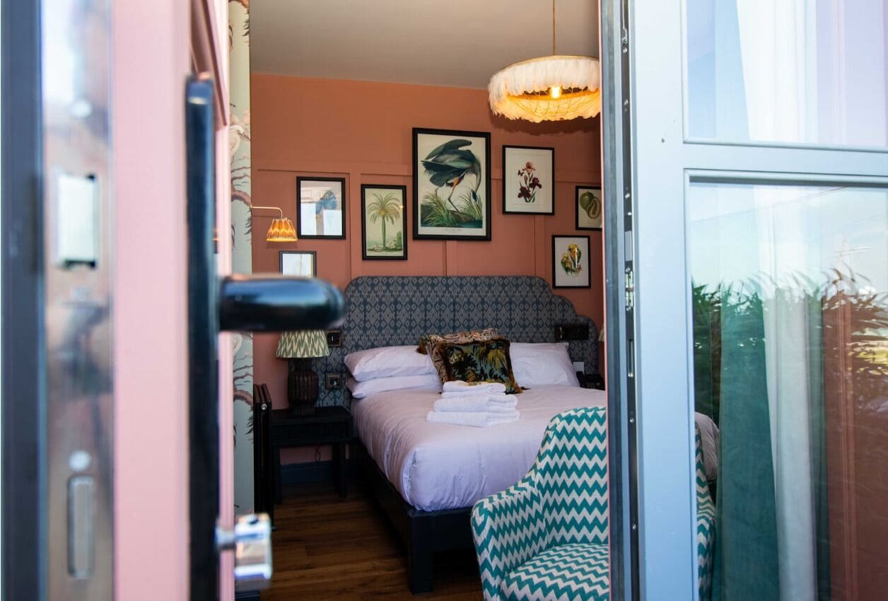 A bedroom with a patterned bed, a large window, and wall art.