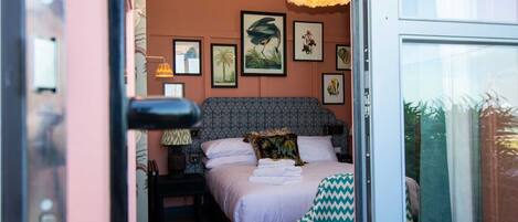 A bedroom with a patterned bed, a large window, and wall art.