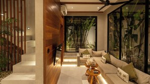 A modern living room with a sofa, a coffee table, and a staircase. - Nanna Villa Unit 4 by Betterplace (Canggu)