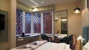 Ein Hotelzimmer mit Bett, Schreibtisch, Stuhl und einem großen Fenster mit Vorhängen.