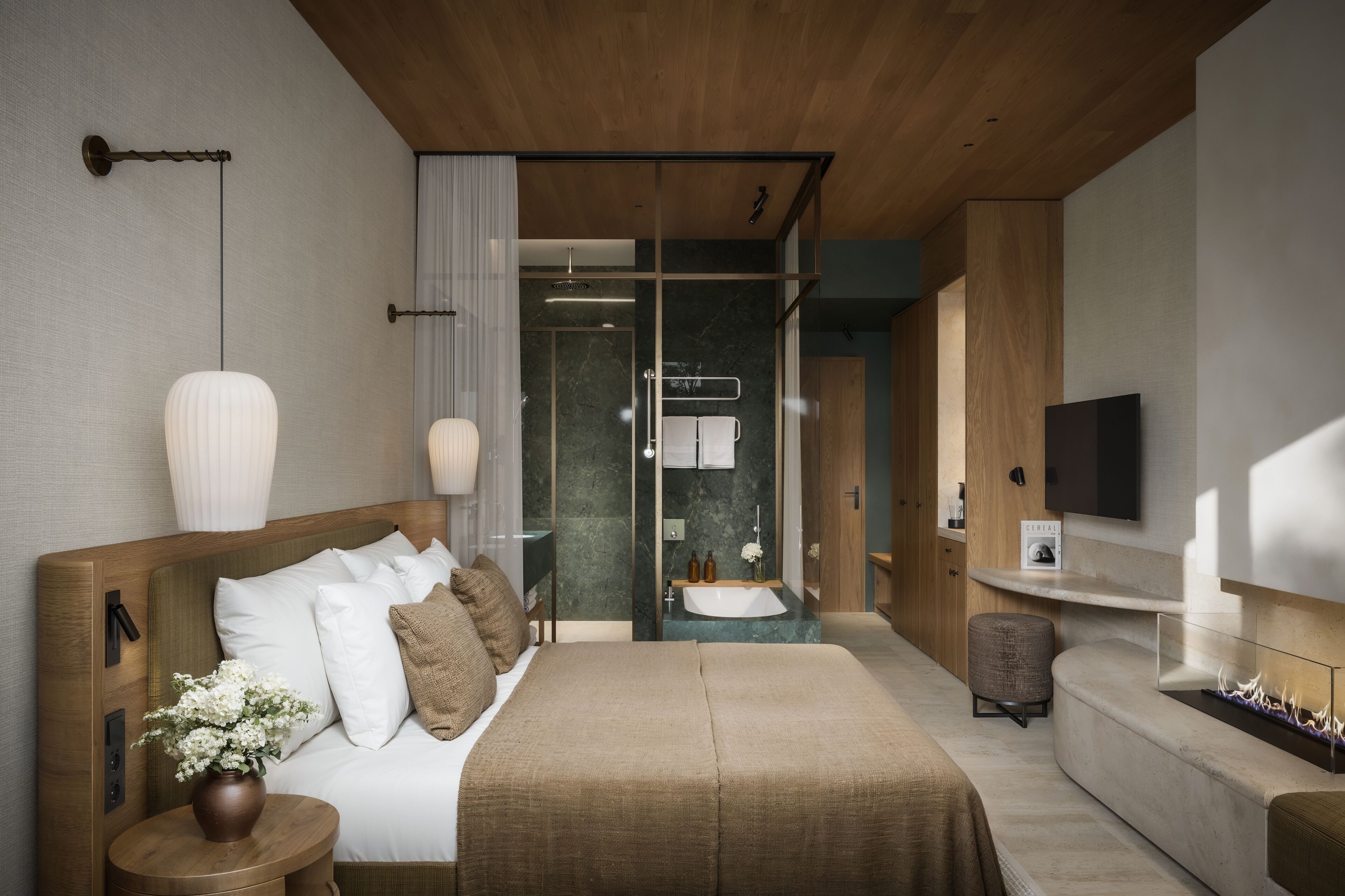 Une chambre moderne avec un grand lit, des tables de chevet, une télévision et une salle de bain équipée d’une douche et d’un lavabo.