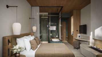 Une chambre moderne avec un grand lit, des tables de chevet, une télévision et une salle de bain équipée d’une douche et d’un lavabo.