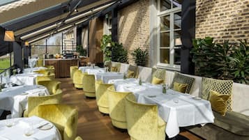 Un restaurante con varias mesas y sillas, una pared de ladrillo y un ventanal.