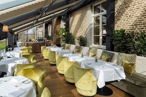 A restaurant with multiple tables and chairs, a brick wall, and a window. - Van Oys Maastricht Retreat, a Leading Hotel of the World (Eijsden)