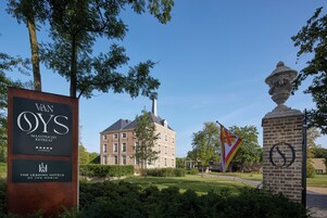 A sign for Van Oys Maastrich Retreat with a brick building in the background.