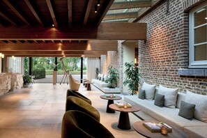 Un amplio espacio al aire libre con pared de ladrillo, vigas de madera y plantas en macetas.