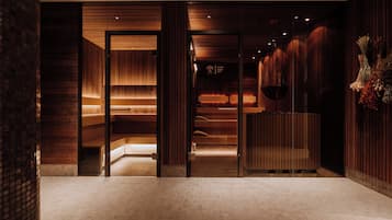Un interior moderno con paneles de madera, una recepción y un cartel de sauna que indica 90°C.