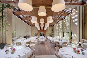 A spacious dining area with multiple tables set for dining, featuring a high ceiling with exposed beams and pendant lighting. - Van Oys Maastricht Retreat, a Leading Hotel of the World (Eijsden)