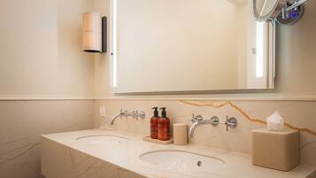 A bathroom with two sinks, a mirror, a towel dispenser, and a soap dispenser.
