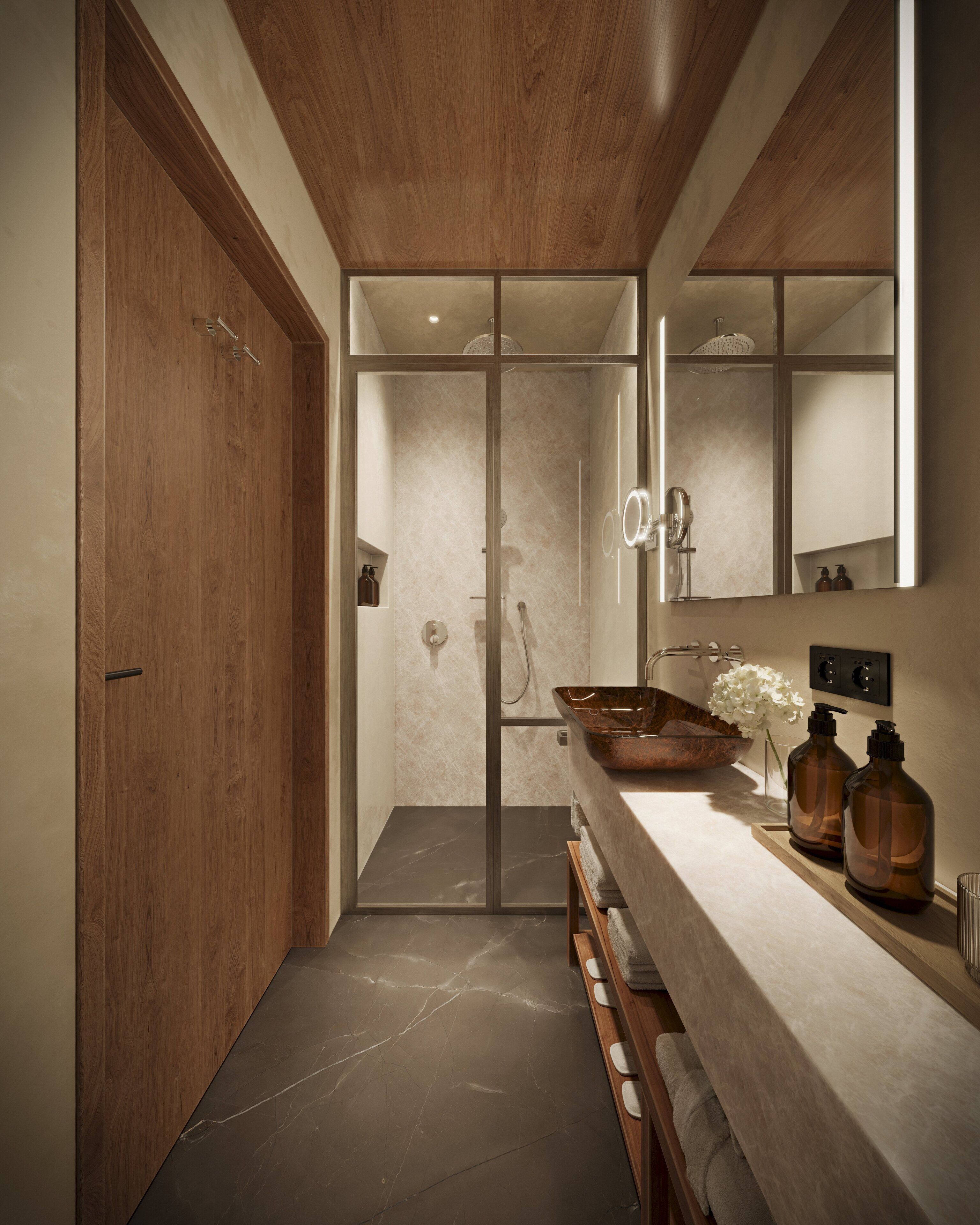 A modern bathroom with a wooden door, a glass shower enclosure, a marble floor, and a large mirror above the sink.