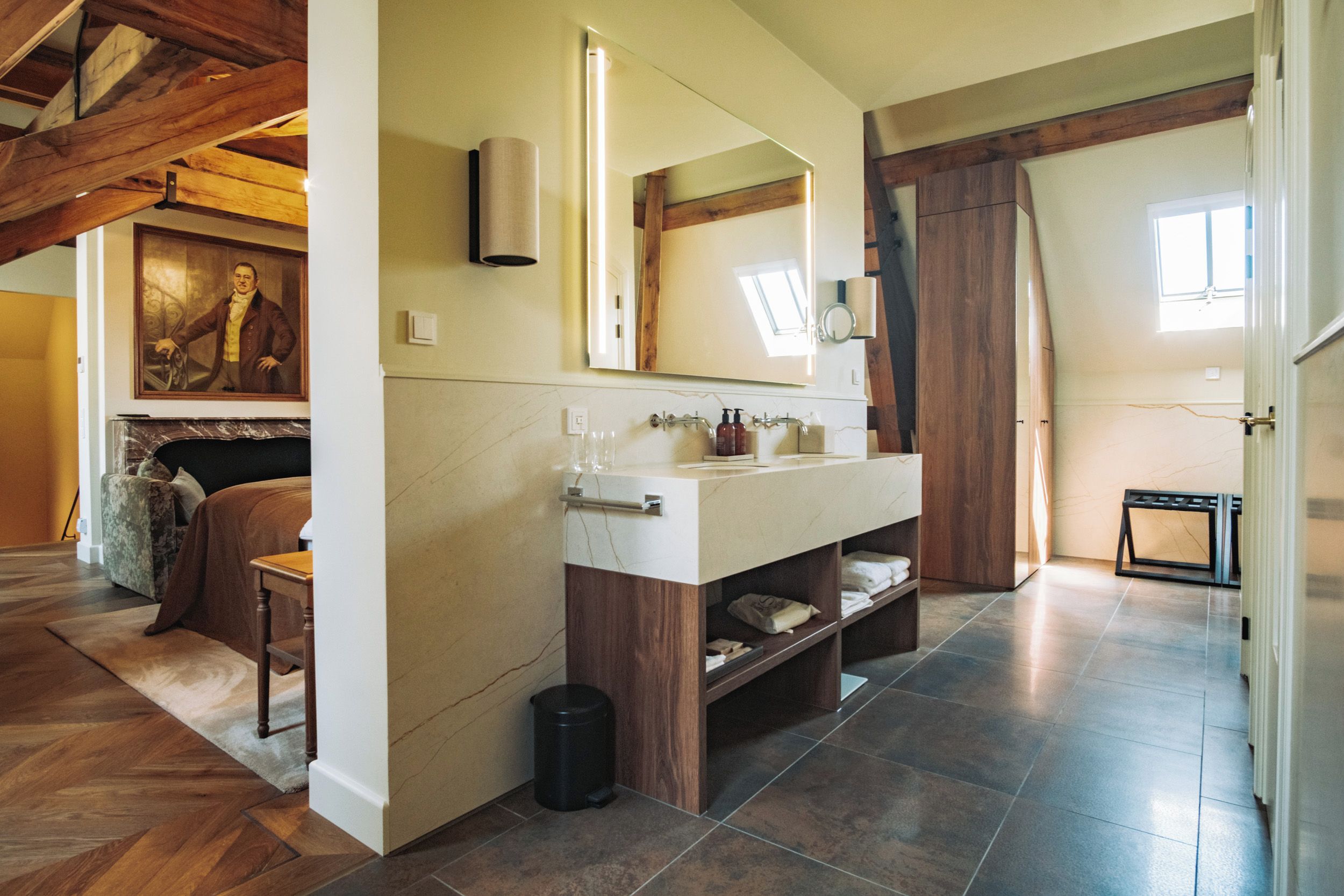 Une salle de bain avec un meuble-lavabo en marbre, un grand miroir et un meuble en bois.