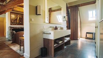 Une salle de bain avec un meuble-lavabo en marbre, un grand miroir et un meuble en bois.