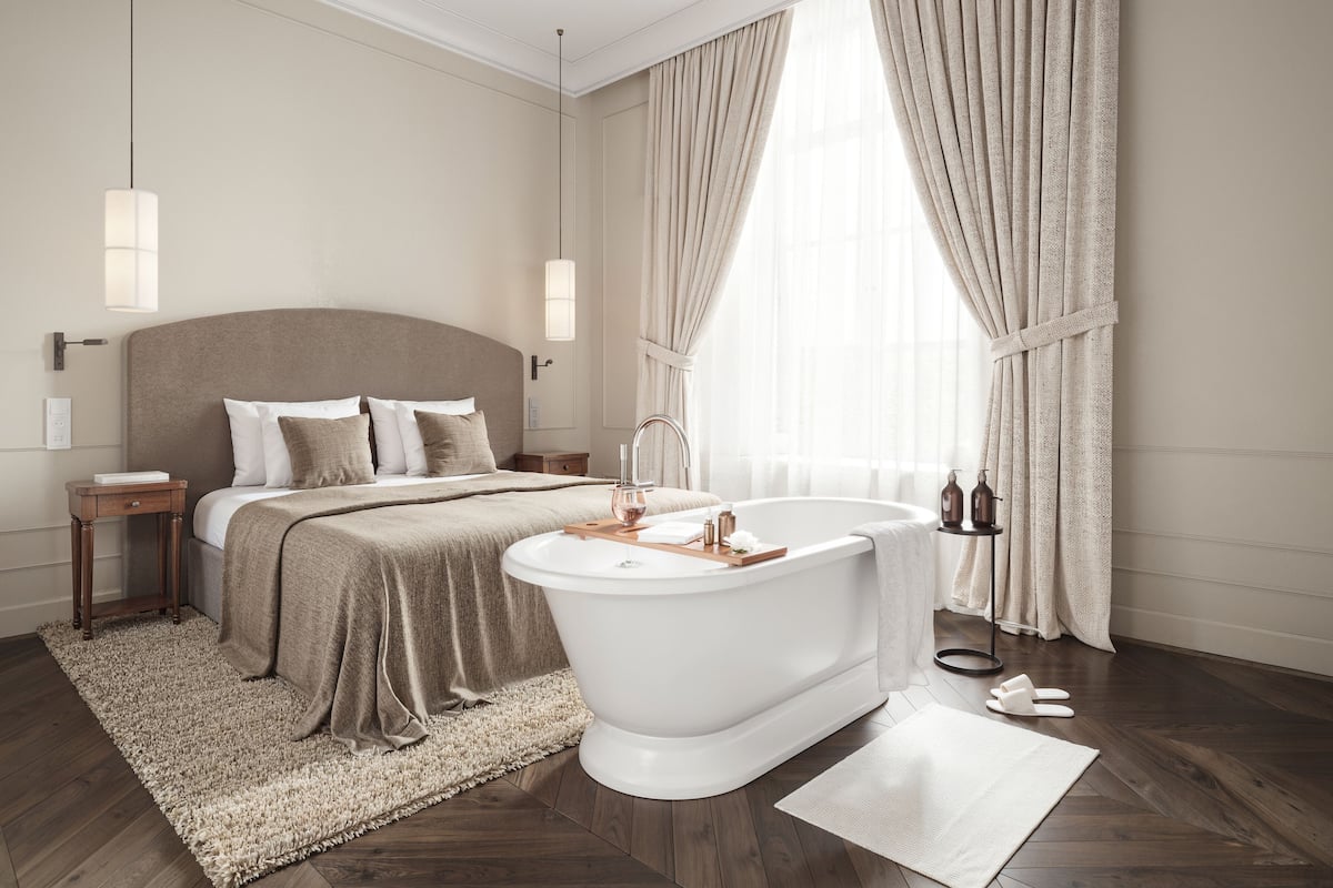Une chambre à coucher moderne avec un grand lit, une baignoire blanche et un plancher en bois.