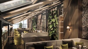 Un restaurant moderne avec de hauts plafonds, des murs en briques apparentes et des sièges verts.