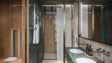 A modern bathroom with two sinks, a shower, and a wooden vanity.